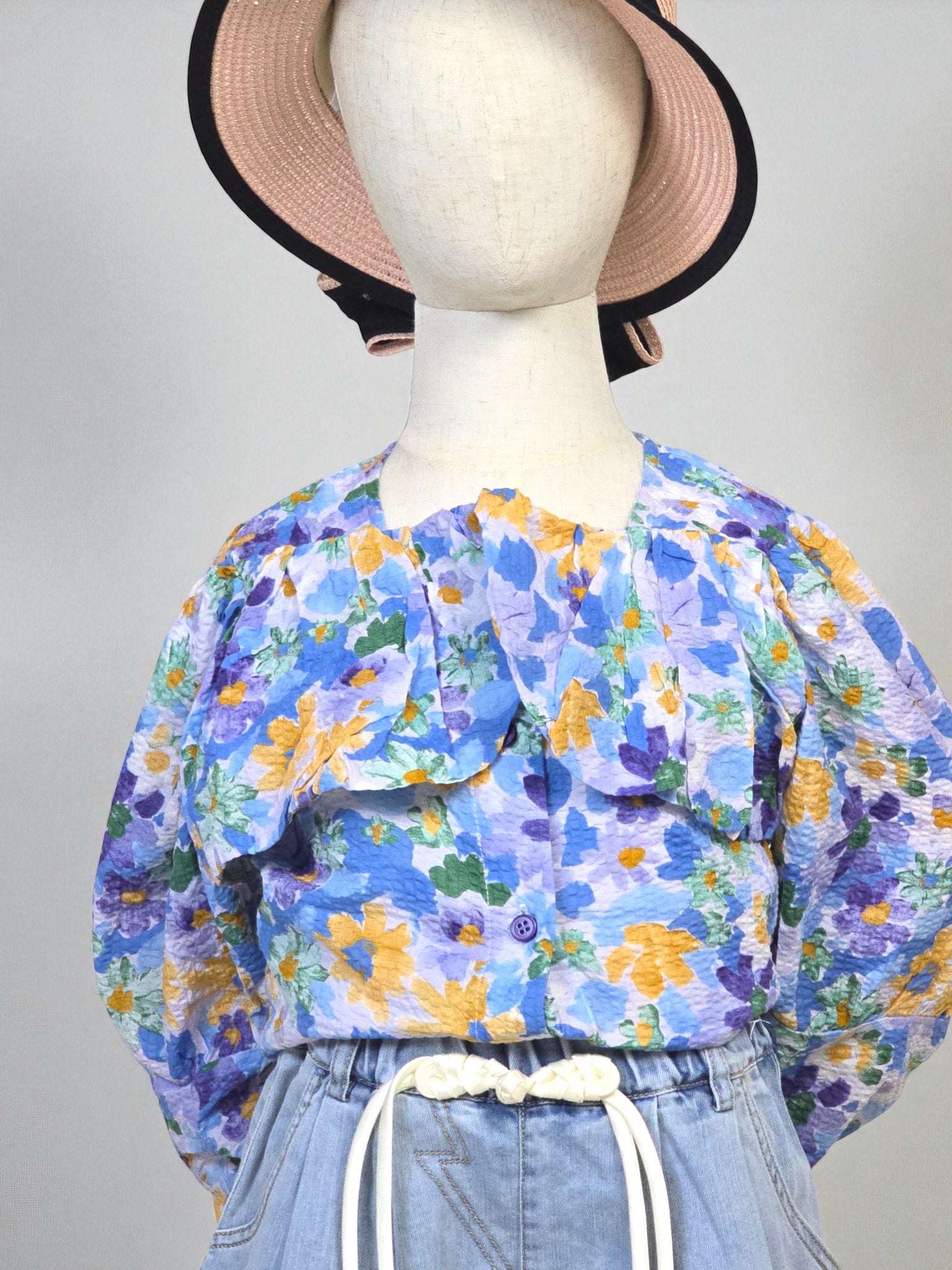 Kids clothing Mannequin wearing a floral blouse and denim shorts with a hat on a white background. Blue