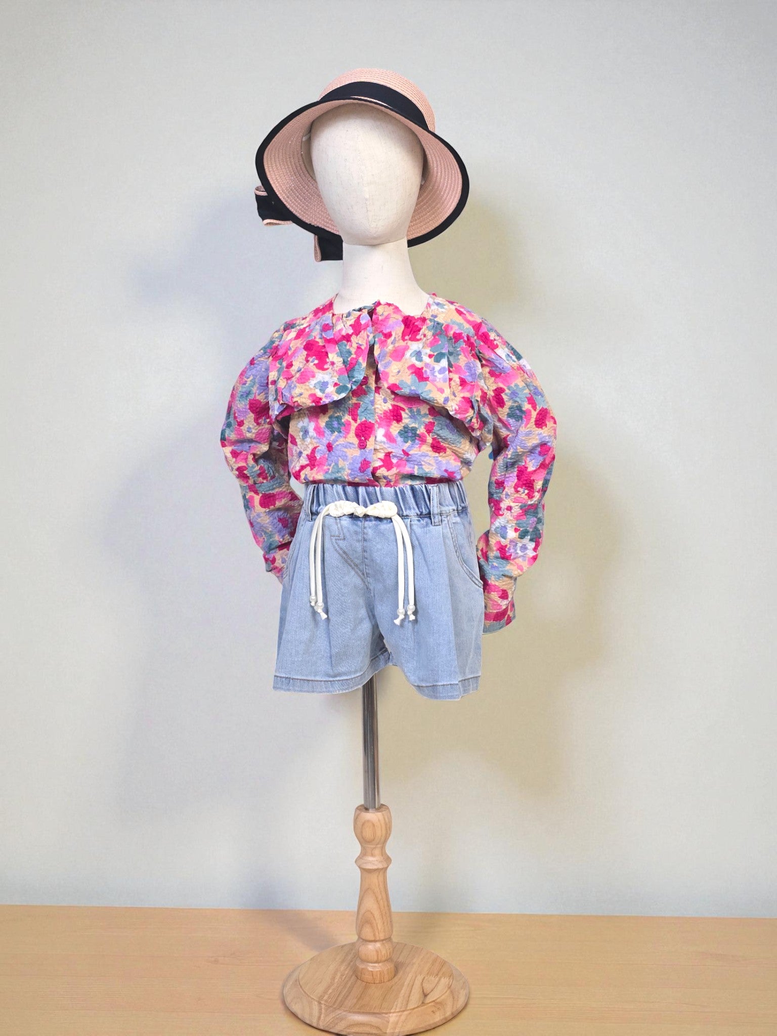 Kids clothing Mannequin wearing a floral blouse and denim shorts with a pink hat on a white background. Pink