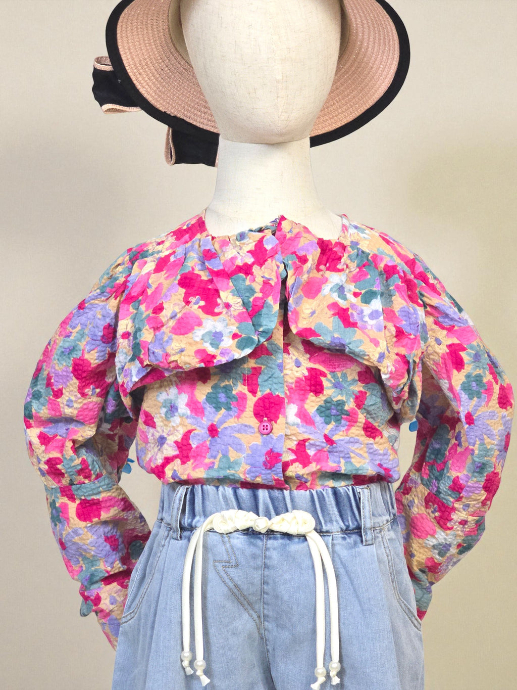 Kids clothing Mannequin wearing a floral blouse and denim shorts with a pink hat on a white background. Pink