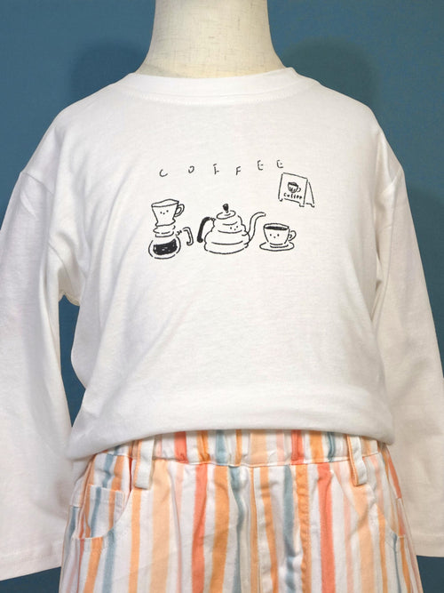 White long-sleeve shirt with coffee-themed graphics on a mannequin against a blue background