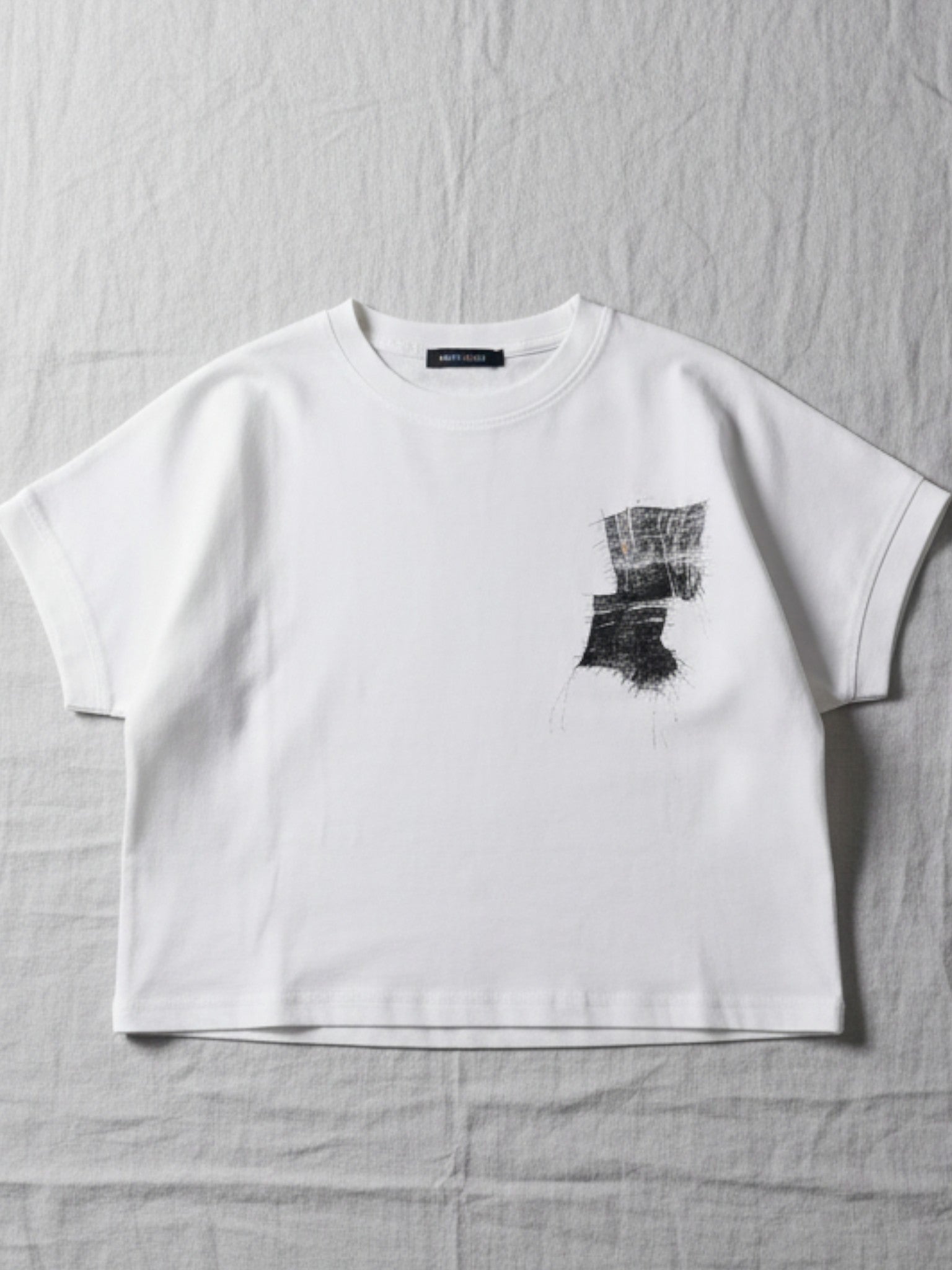 Half Moon Clothing kids' white short-sleeve t-shirt with a textured black abstract graphic, premium breathable fabric for all-day comfort.