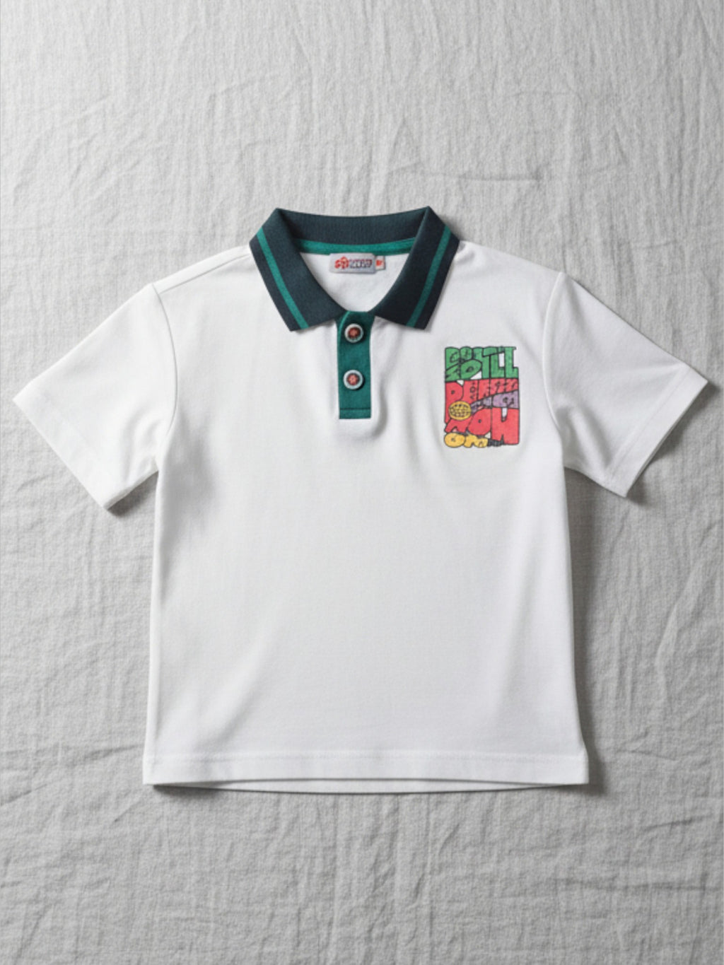 Children's white short-sleeve polo shirt featuring a dark teal contrast collar and placket with a colorful block graphic on the chest.