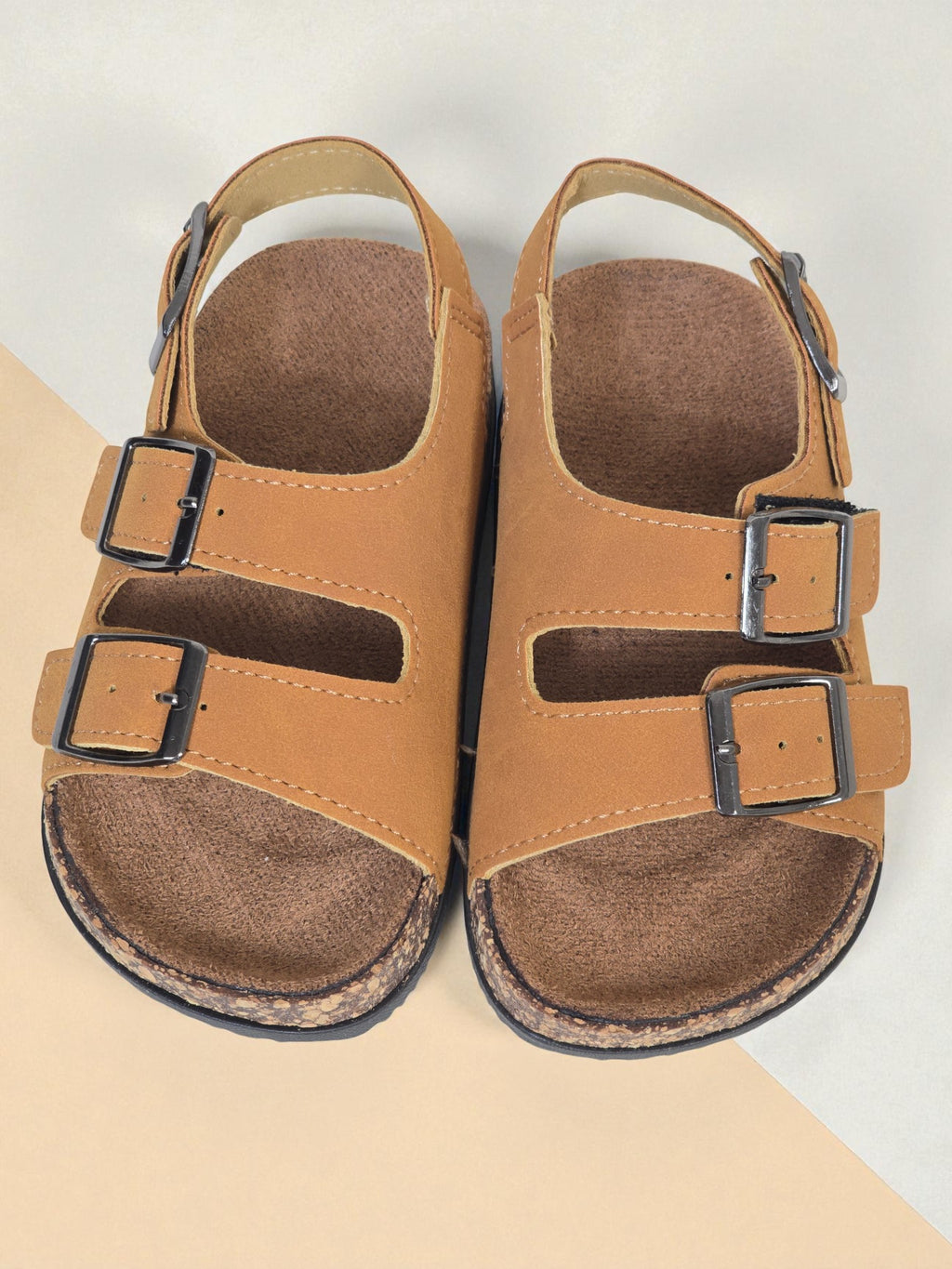 Pair of Kids Birkenstock style brown sandals with buckles on a light surface. Brown