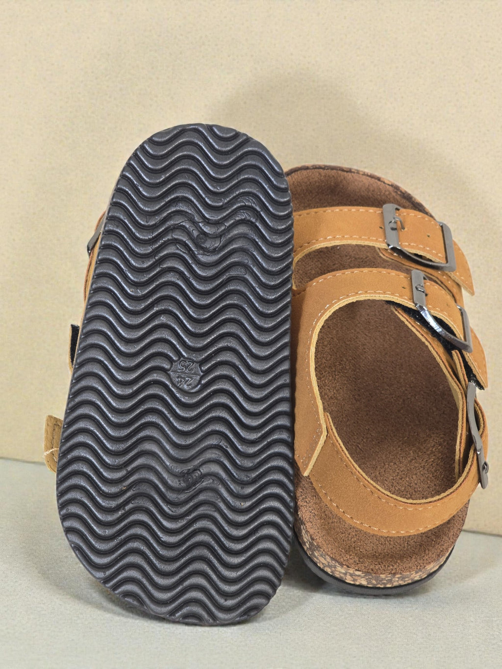 Pair of Kids Birkenstock style brown sandals with buckles on a light surface. Brown