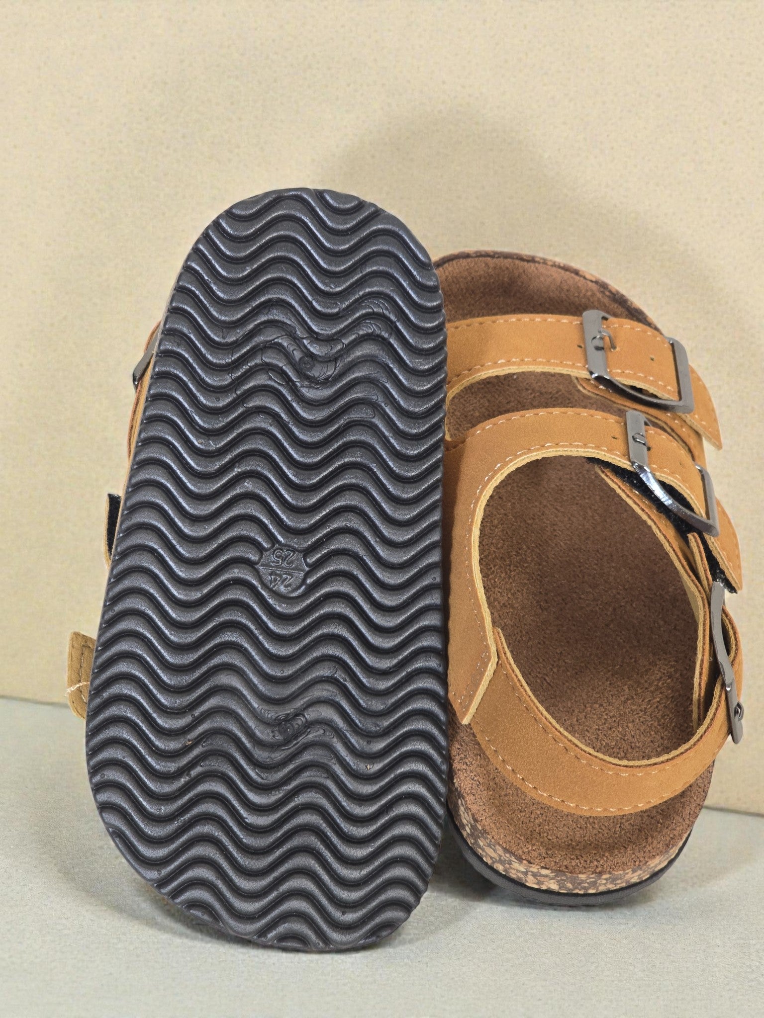 Pair of Kids Birkenstock style brown sandals with buckles on a light surface. Brown