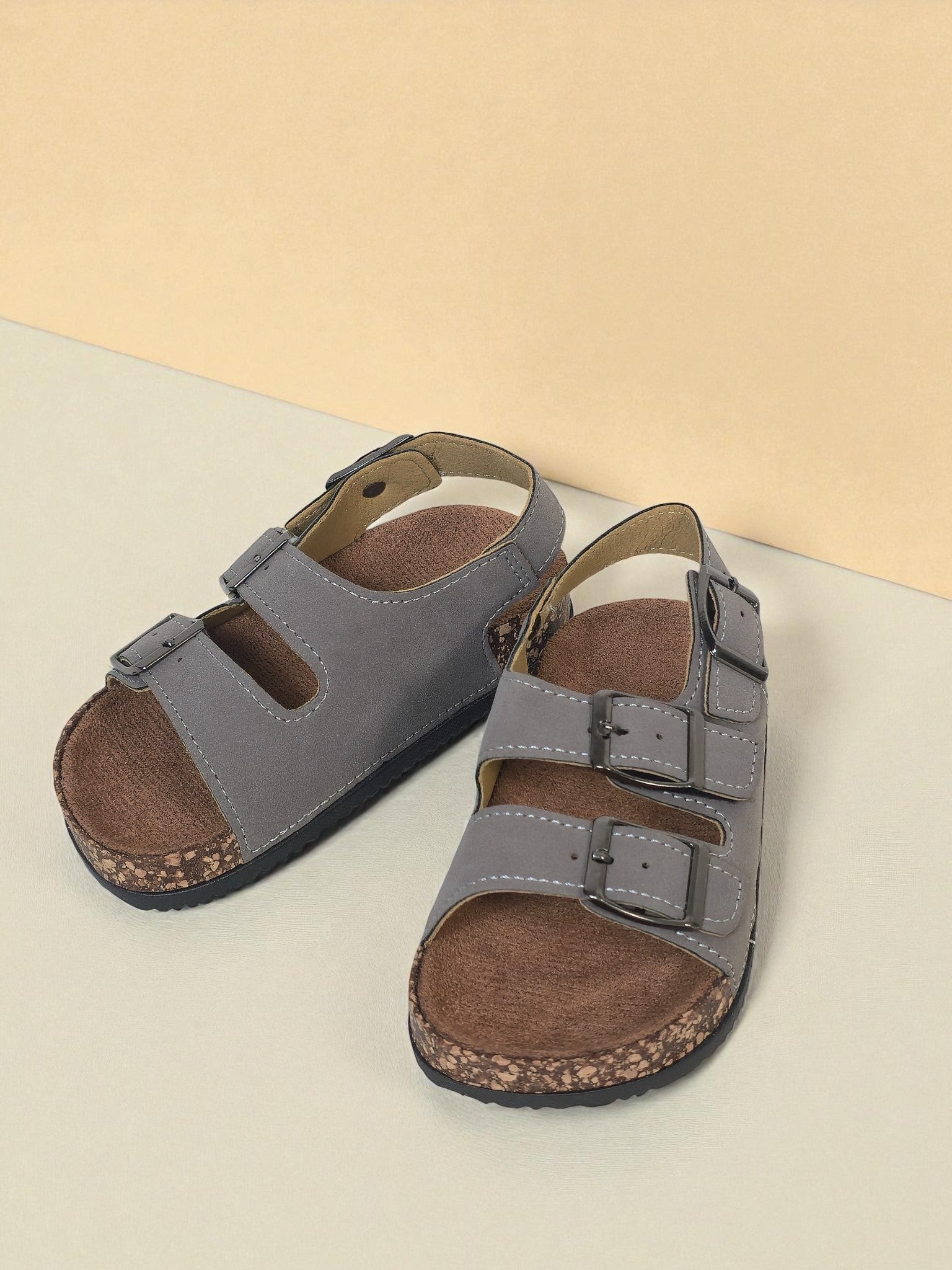 Pair of Kids Birkenstock style sandals with buckles on a light gray surface. Gray