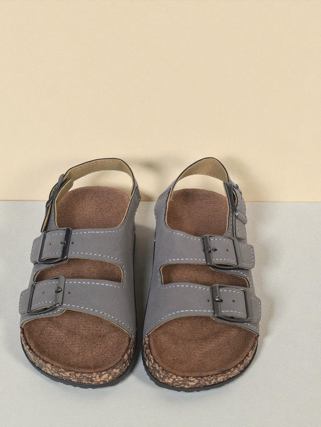 Pair of Kids Birkenstock style sandals with buckles on a light gray surface. Gray