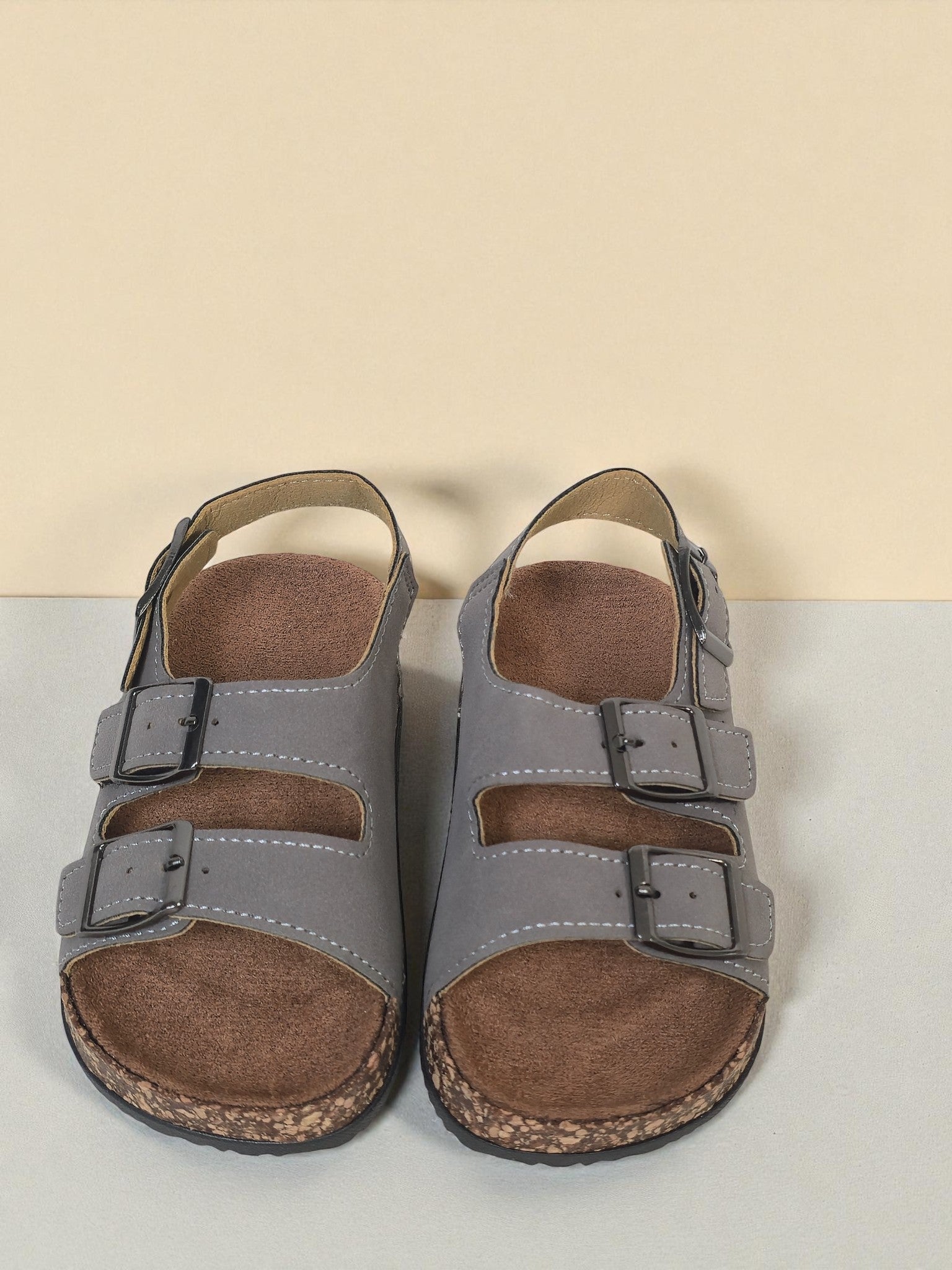 Pair of Kids Birkenstock style sandals with buckles on a light gray surface. Gray