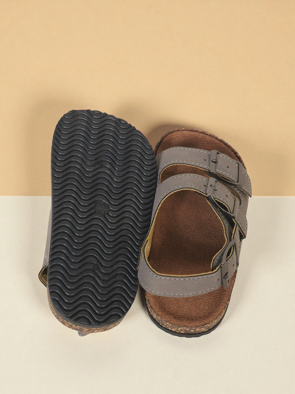 Pair of Kids Birkenstock style sandals with buckles on a light gray surface. Gray