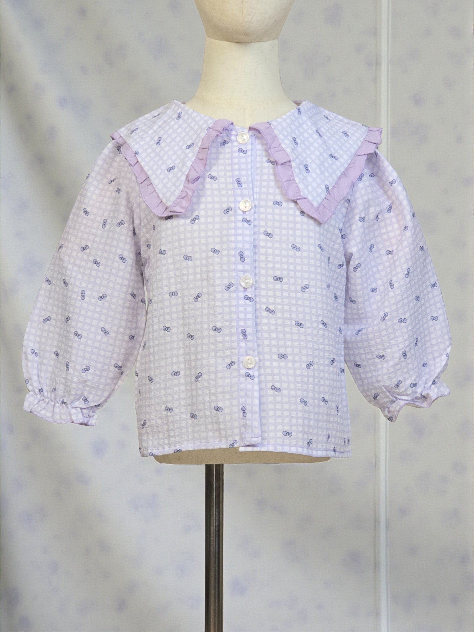 Lavender checkered blouse with ruffled collar on a mannequin against a neutral background. Lilac