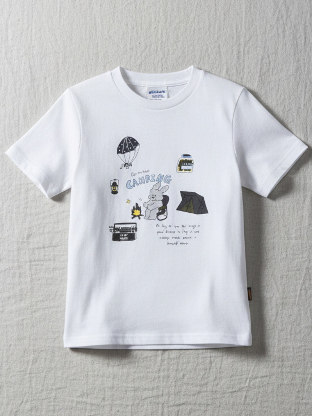 Children's white short-sleeve t-shirt featuring a playful "Camping" themed illustration with a bunny by a campfire, a tent, and a parachute.
