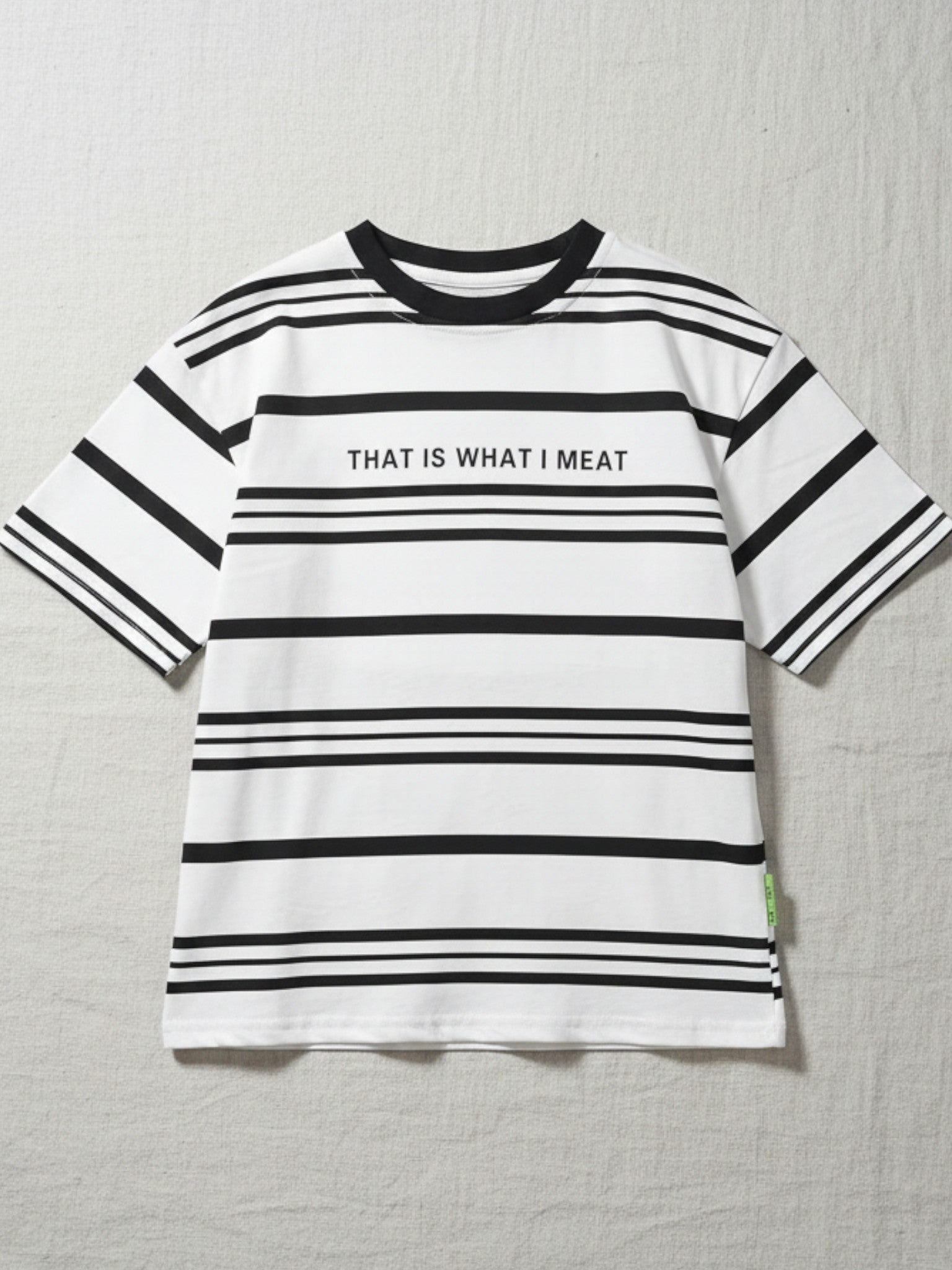 Children's white short-sleeve t-shirt with varied horizontal black stripes and "THAT IS WHAT I MEAT" printed across the chest in black.