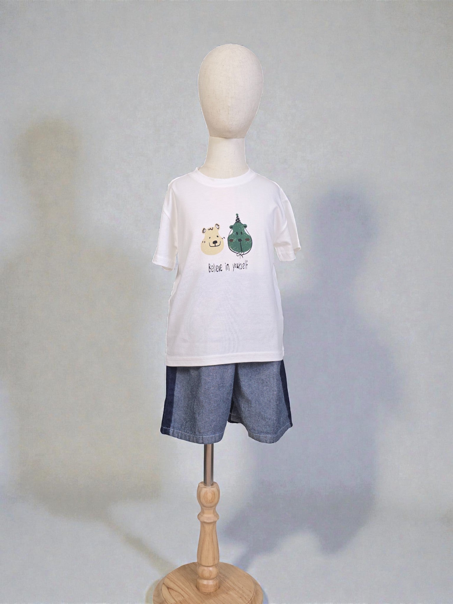 white t-shirt with graphics and denim shorts on a light gray background