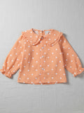 A young child wearing a breathable, orange polka dot button-up top with a relaxed fit, perfect for comfortable everyday play.