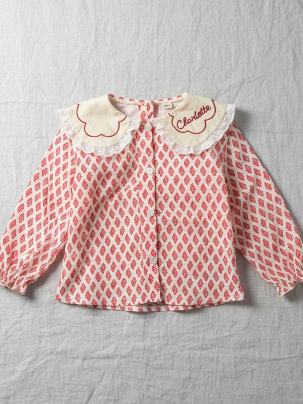Girls' long-sleeve blouse featuring a red floral blossom print and a white embroidered scalloped collar with lace trim.