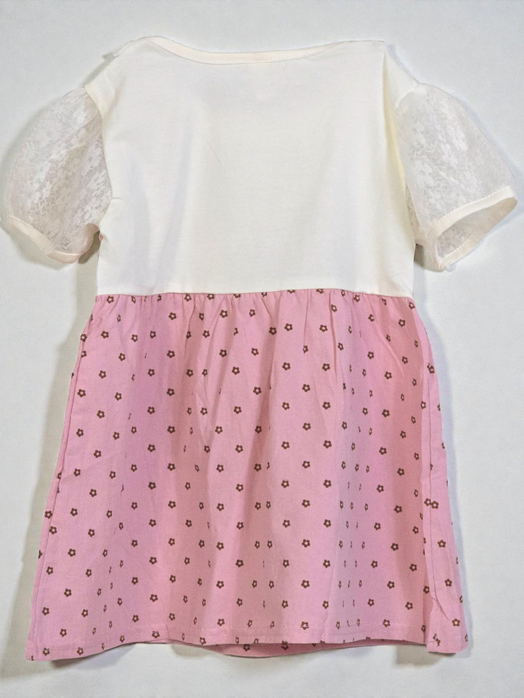 White top with lace sleeves and a pink skirt with floral pattern on a white background. Pink 3