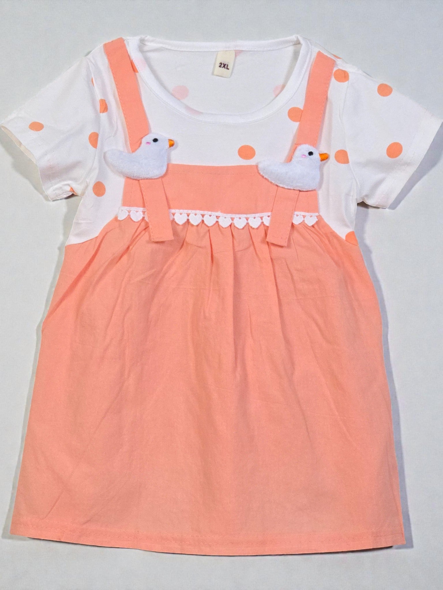 Peach-colored dress with white polka dots and bird design on a gray background. Apricot