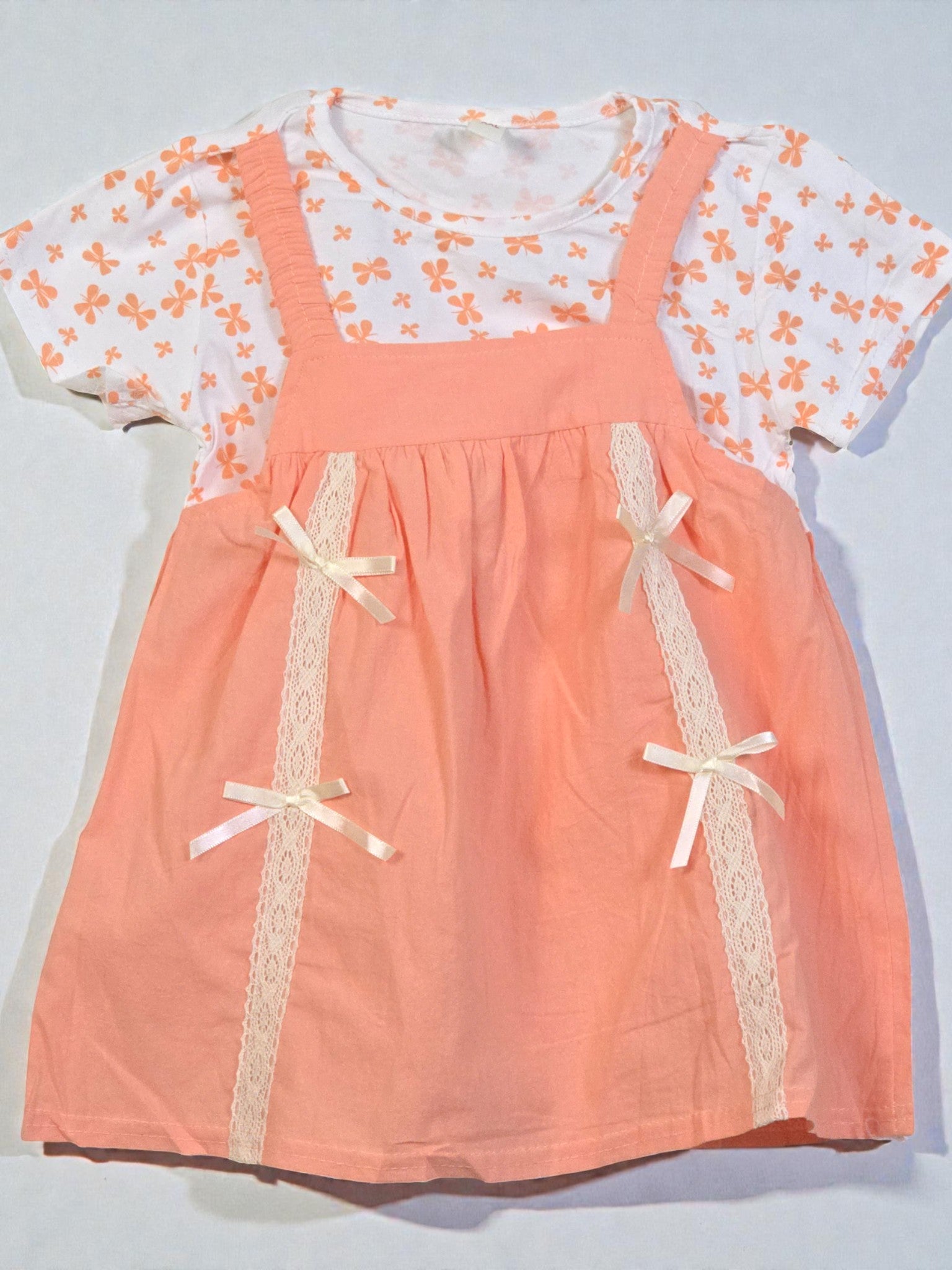Peach-colored dress with lace details and a white floral top on a light gray background. Pumpkin