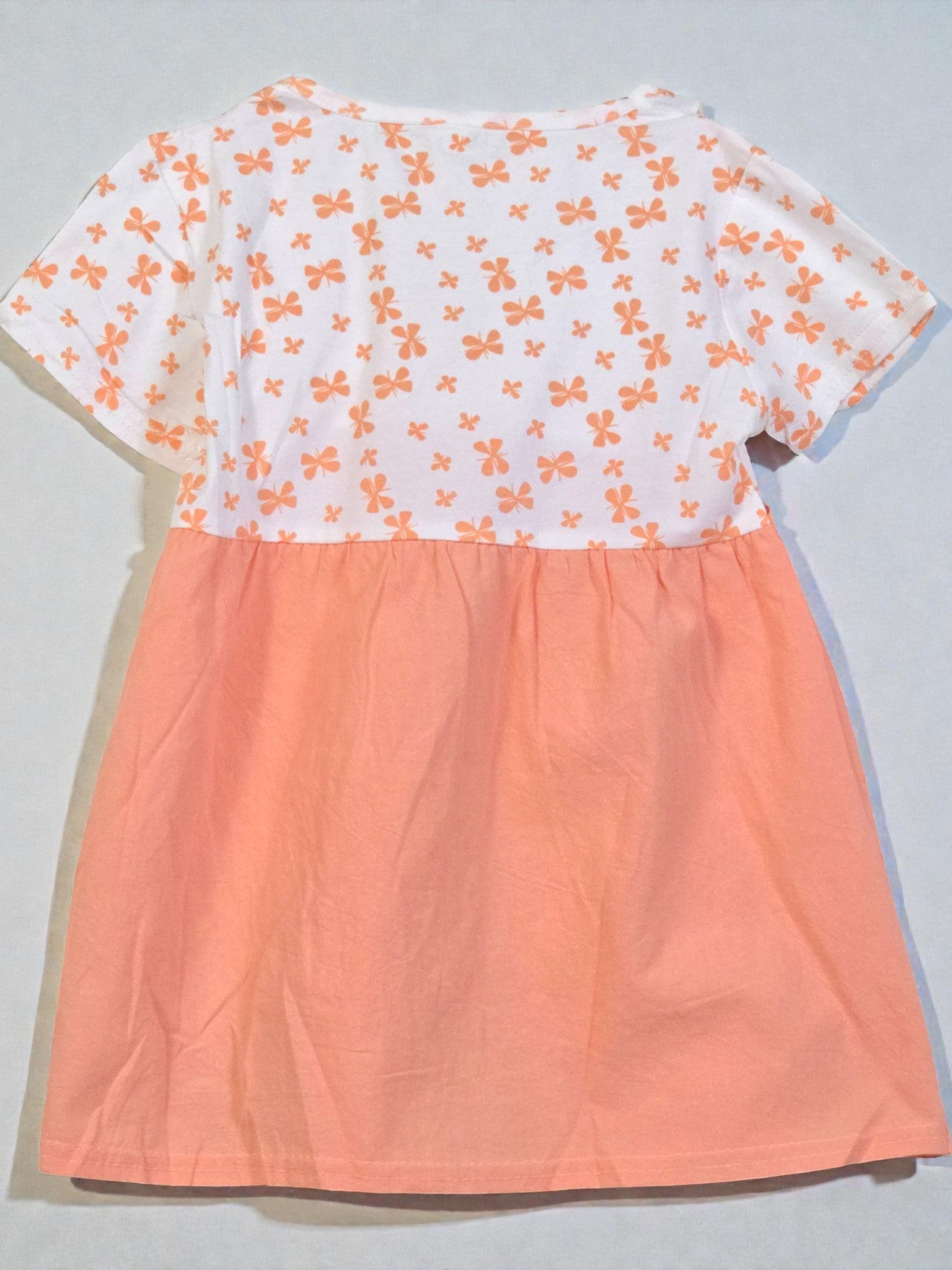 Peach-colored dress with lace details and a white floral top on a light gray background. Pumpkin