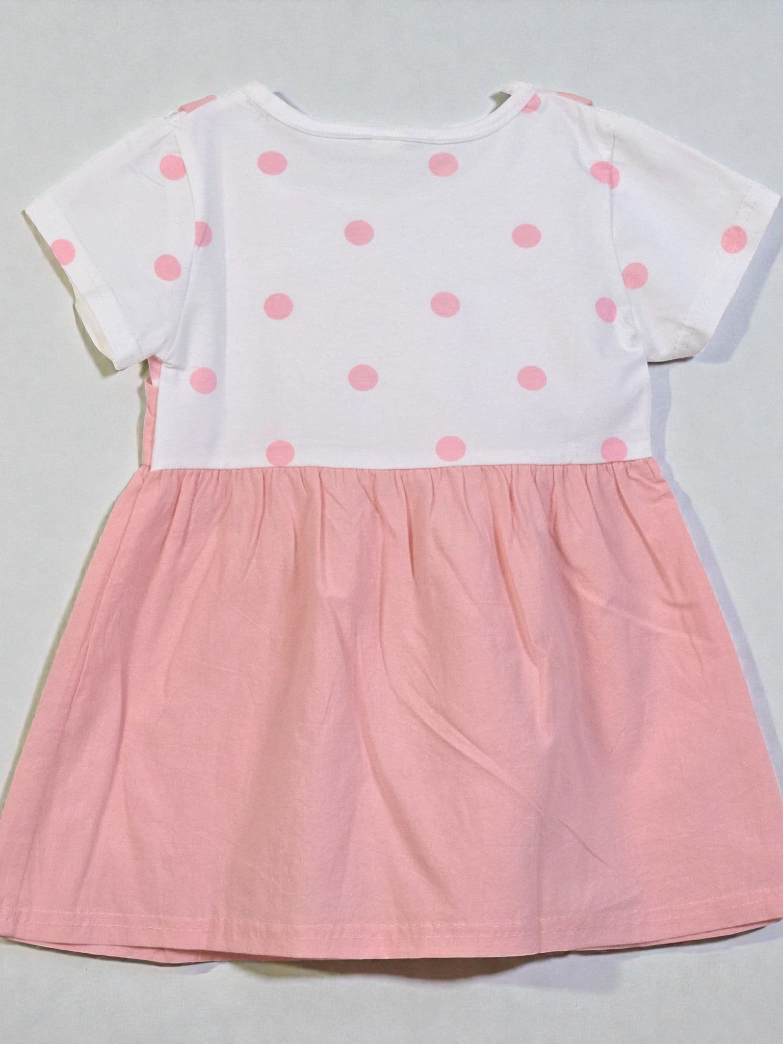 White top with pink polka dots and pink skirt on a light gray background. Pink 6