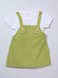 Green pinafore dress with floral details over a white t-shirt with black polka dots. Olive