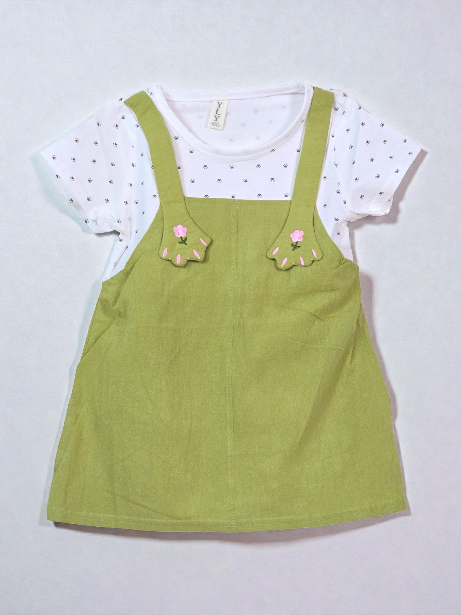 Green pinafore dress with floral details over a white t-shirt with black polka dots. Olive
