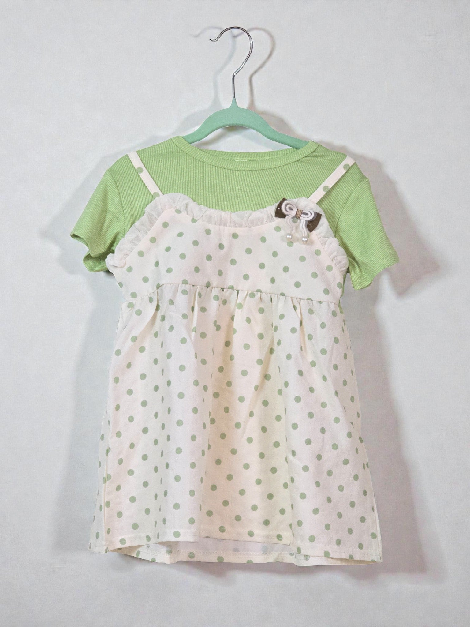 Green top with a polka dot dress on a hanger against a white background. Polka Dots