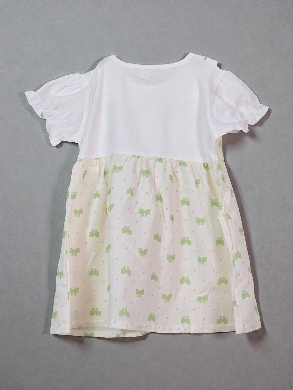 White top with a patterned beige skirt on a gray background. Butterfly