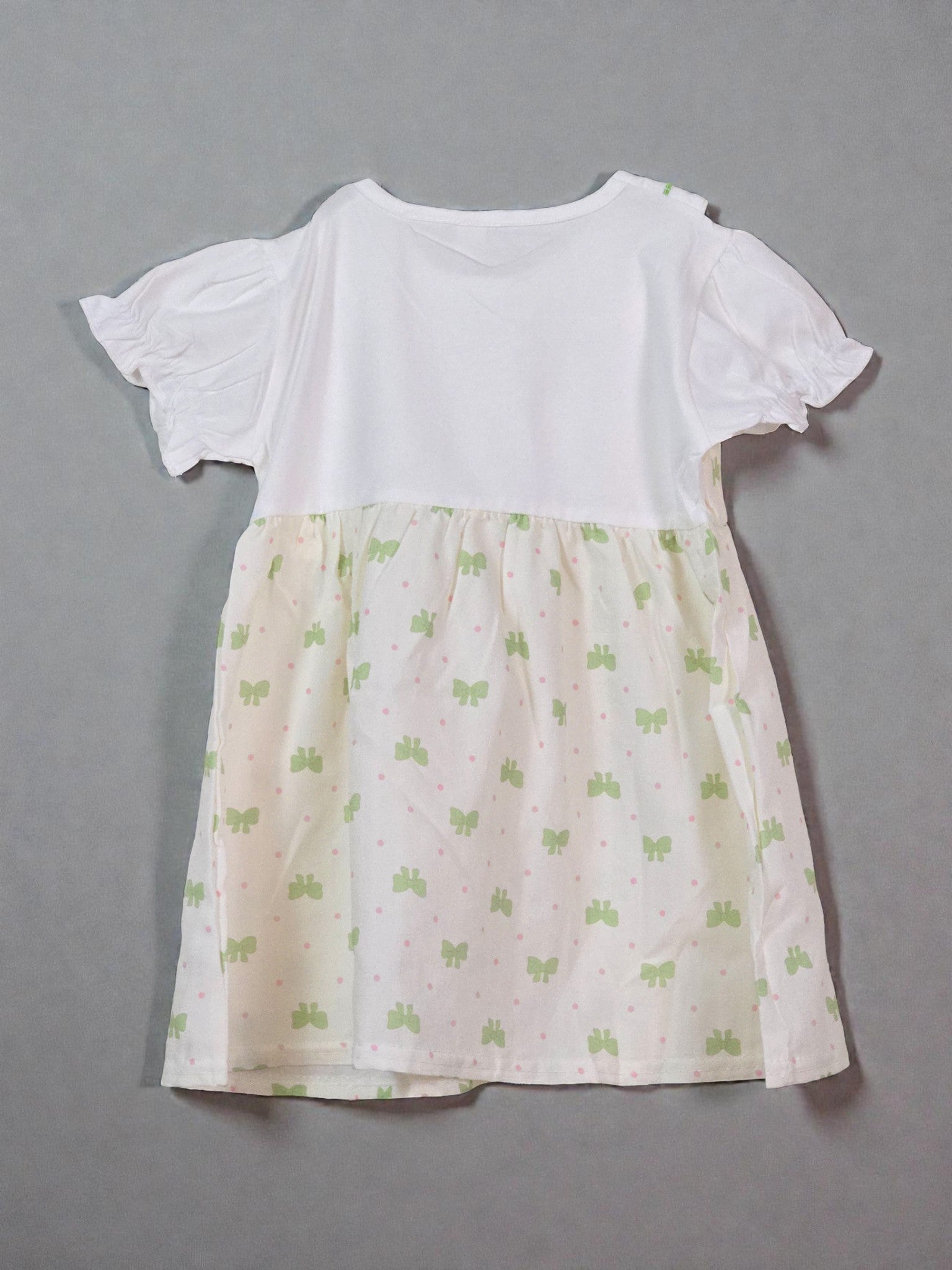 White top with a patterned beige skirt on a gray background. Butterfly