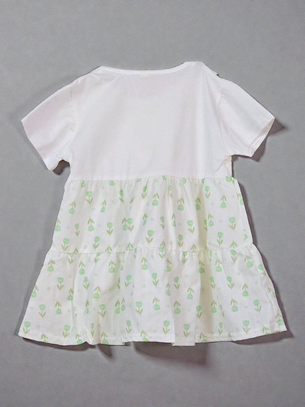 White dress with green floral pattern on a gray background. Fir