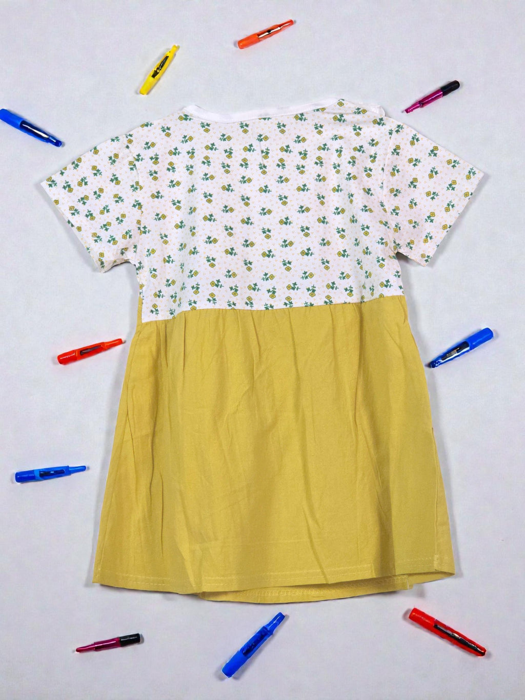 Yellow dress with floral top on a light gray background. Yellow