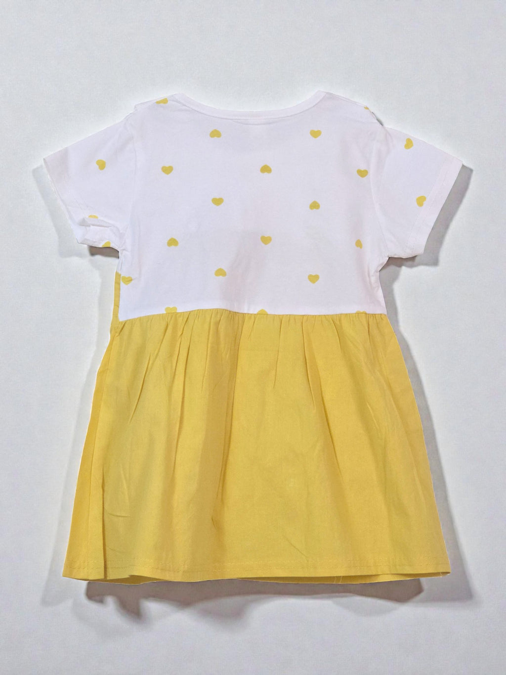 Yellow dress with white collar and red carrot design on a gray background. Carrot