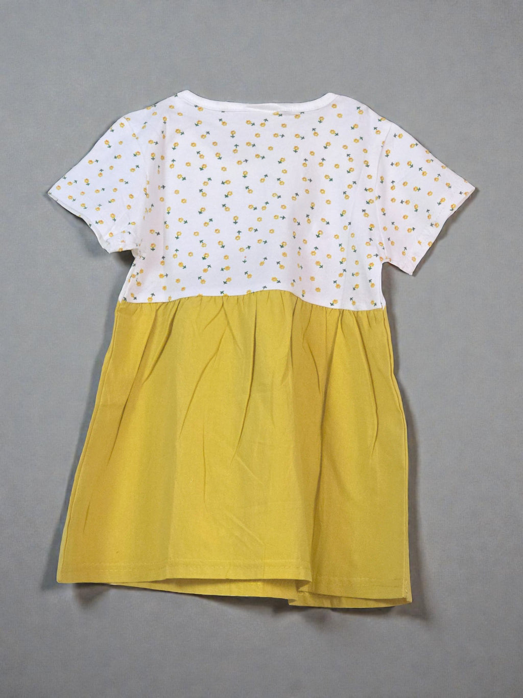Yellow dress with white polka dot top on a light gray background with star patterns. Bowtie