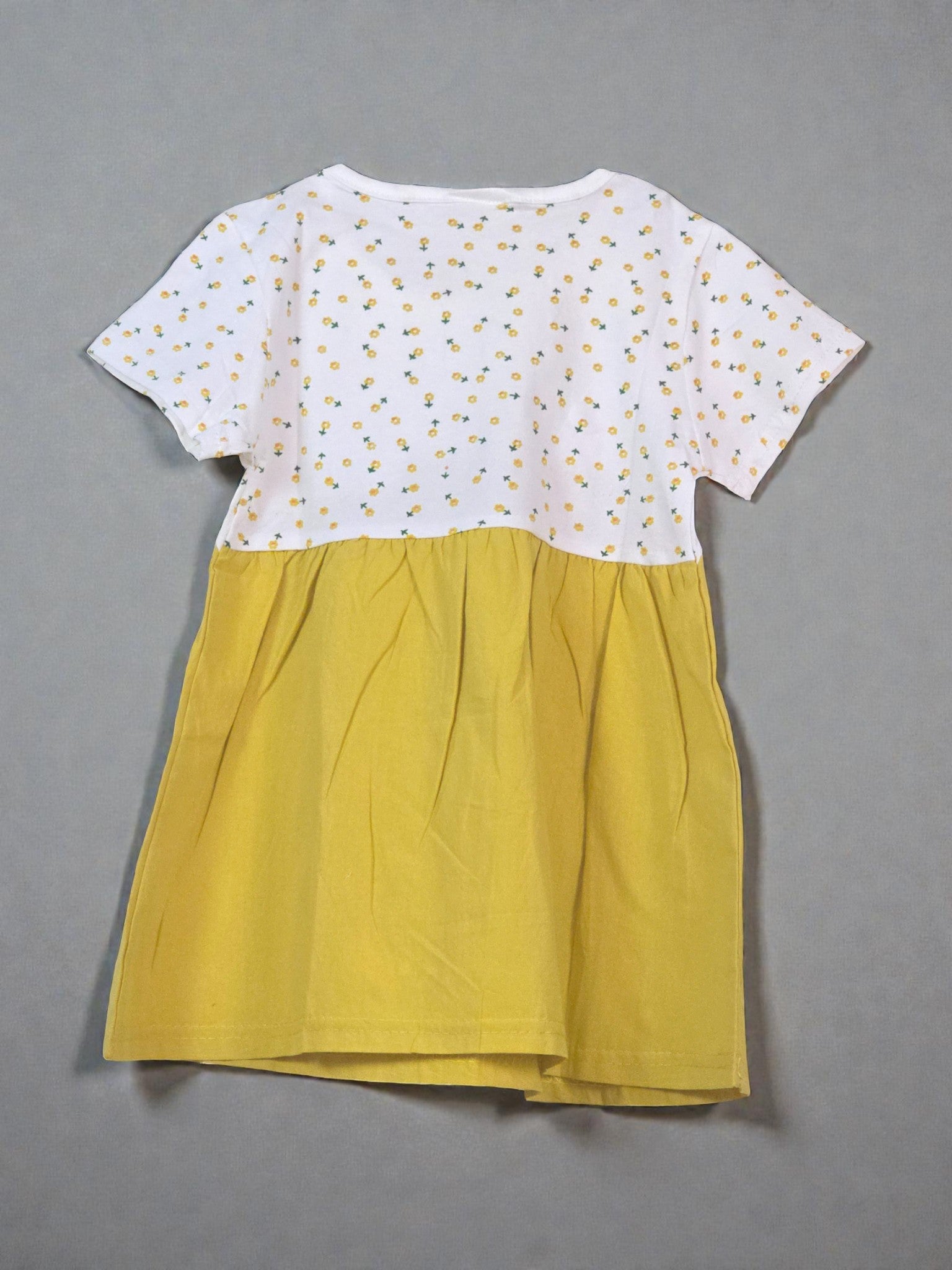 Yellow dress with white polka dot top on a light gray background with star patterns. Bowtie
