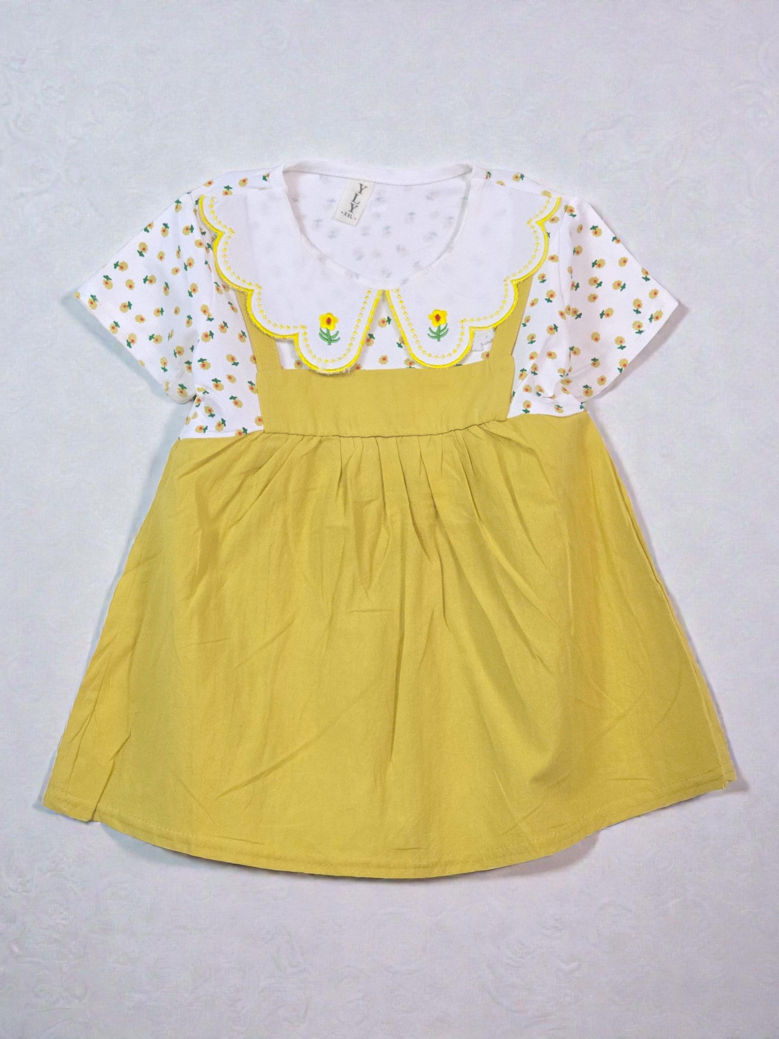 Yellow dress with white floral top on a light gray background. Floral