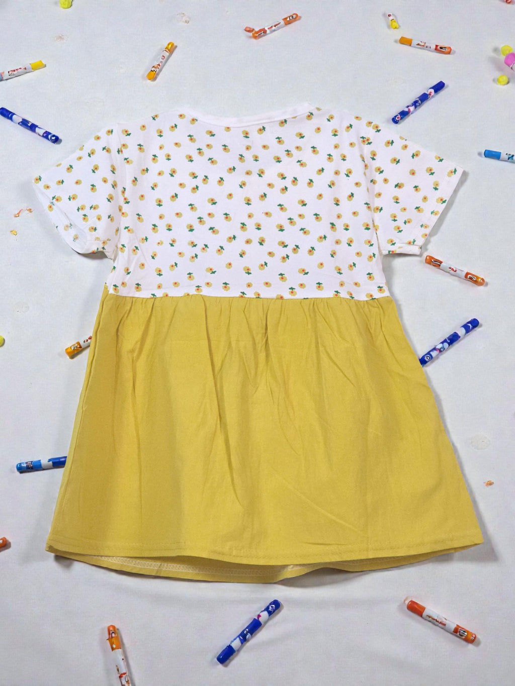 Yellow dress with white floral top on a light gray background. Floral