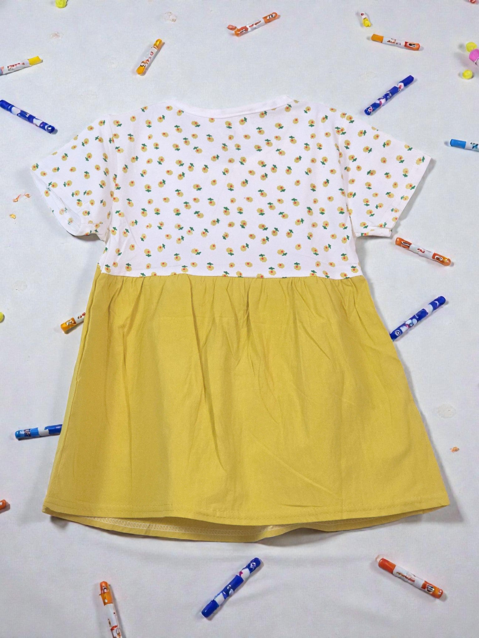 Yellow dress with white floral top on a light gray background. Floral