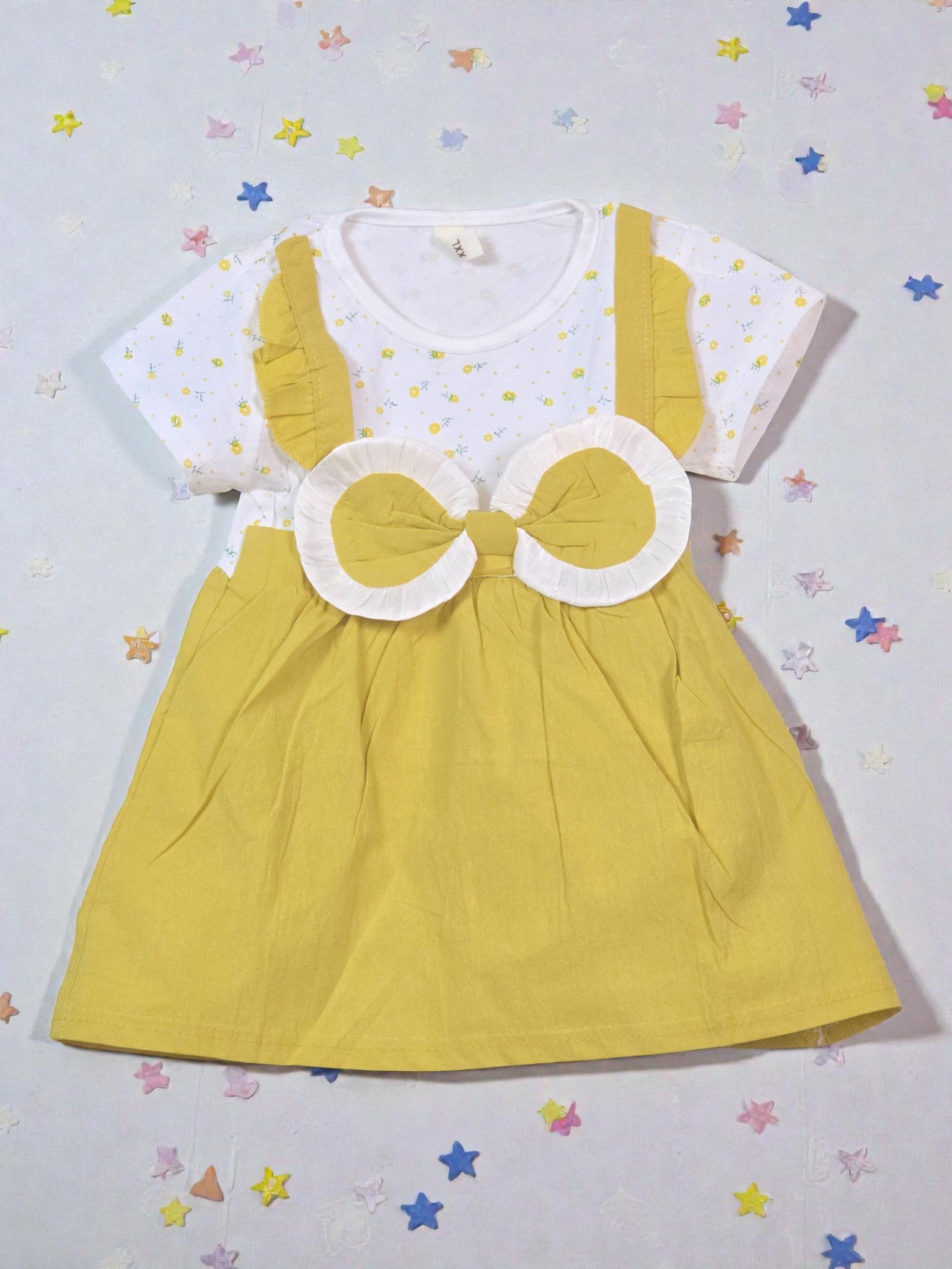 Yellow dress with white polka dot top on a light gray background with star patterns. Bowtie