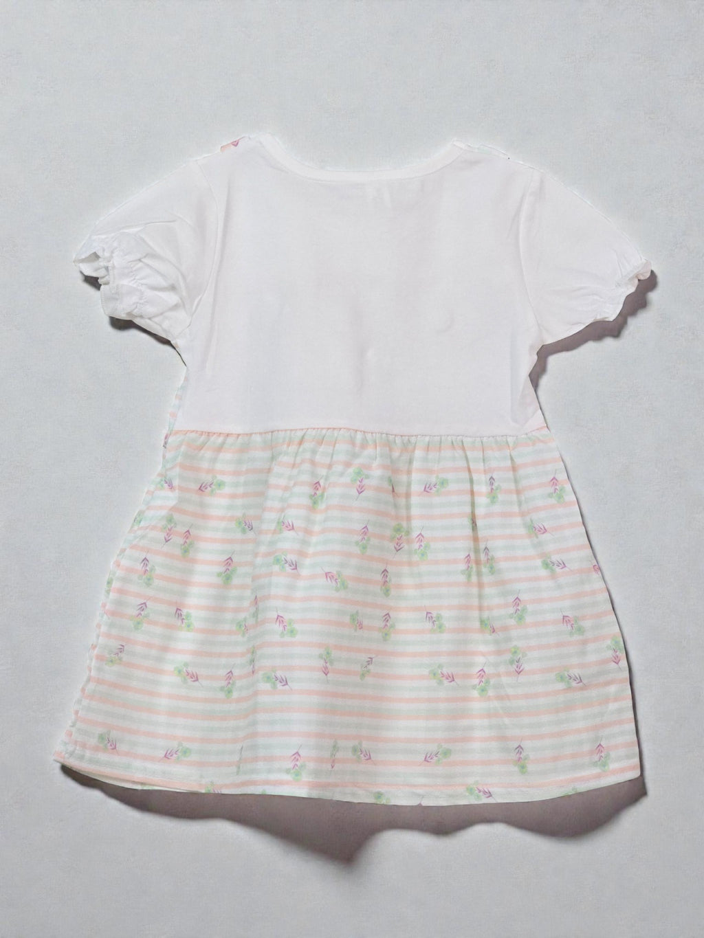 White dress with a subtle pattern on a light gray background. Floral