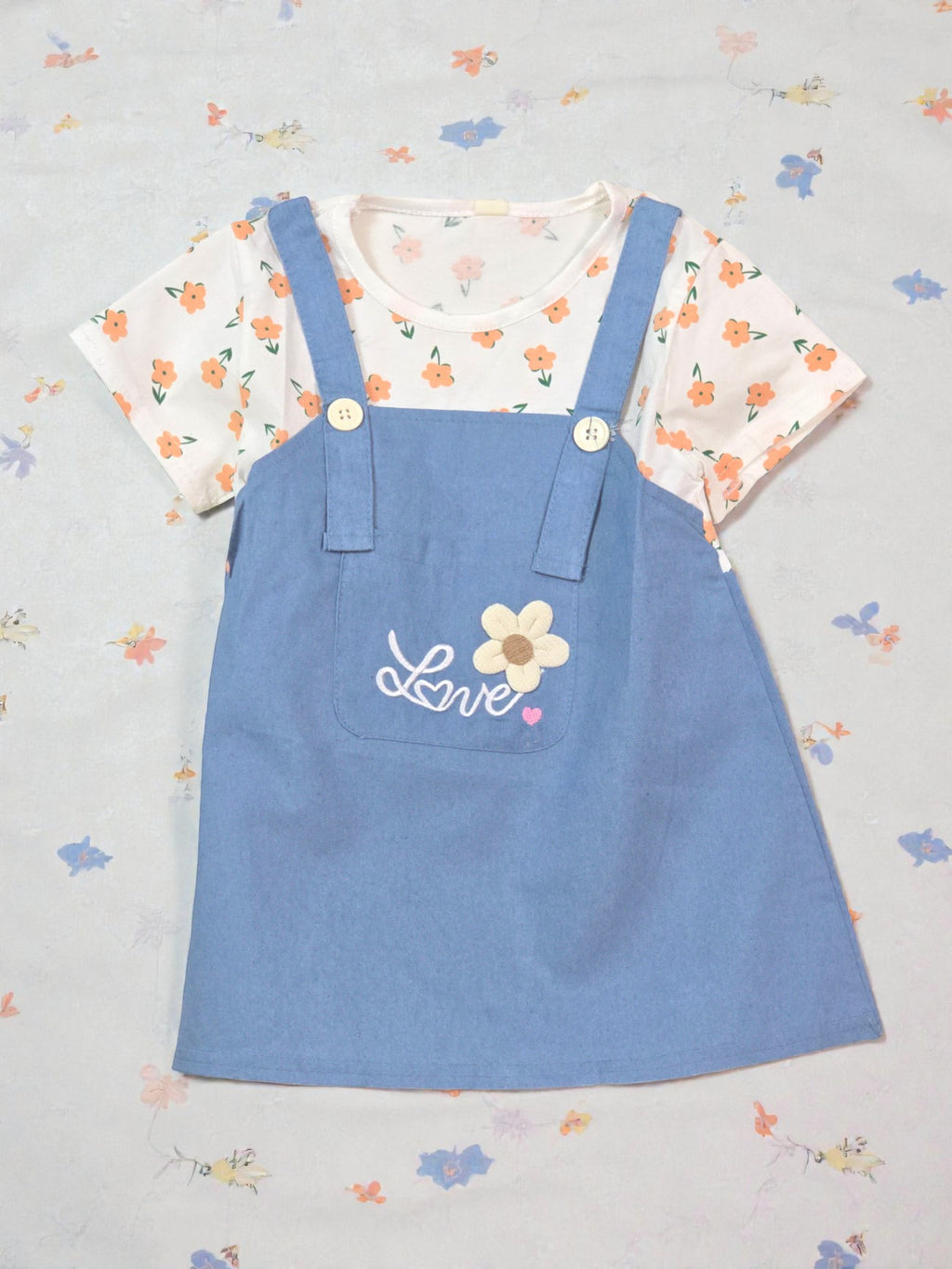 Blue pinafore dress with floral top on a light gray background Dark blue