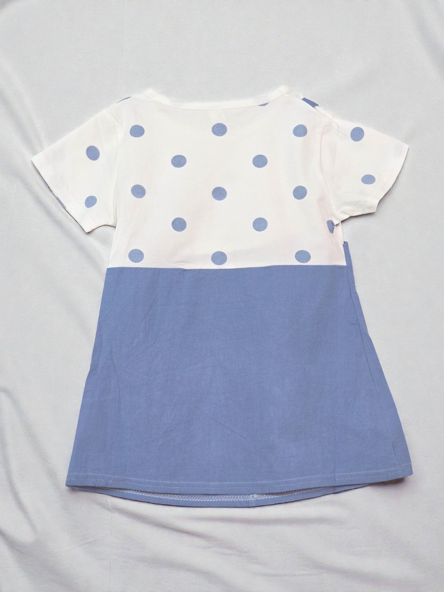 White t-shirt with blue polka dots and a blue bottom section on a gray background Navy