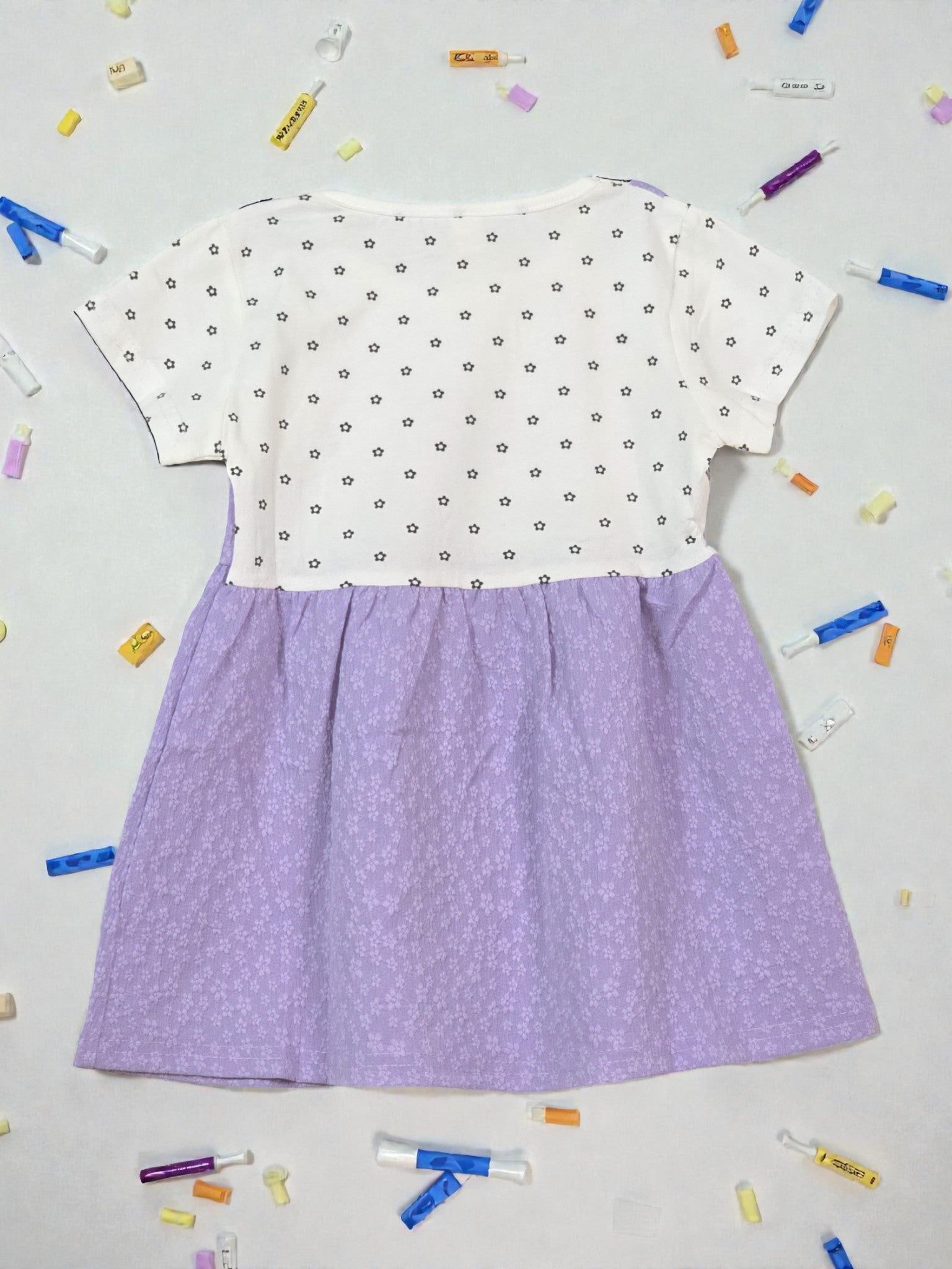 White top with black floral pattern and purple skirt on a light gray background. Violet