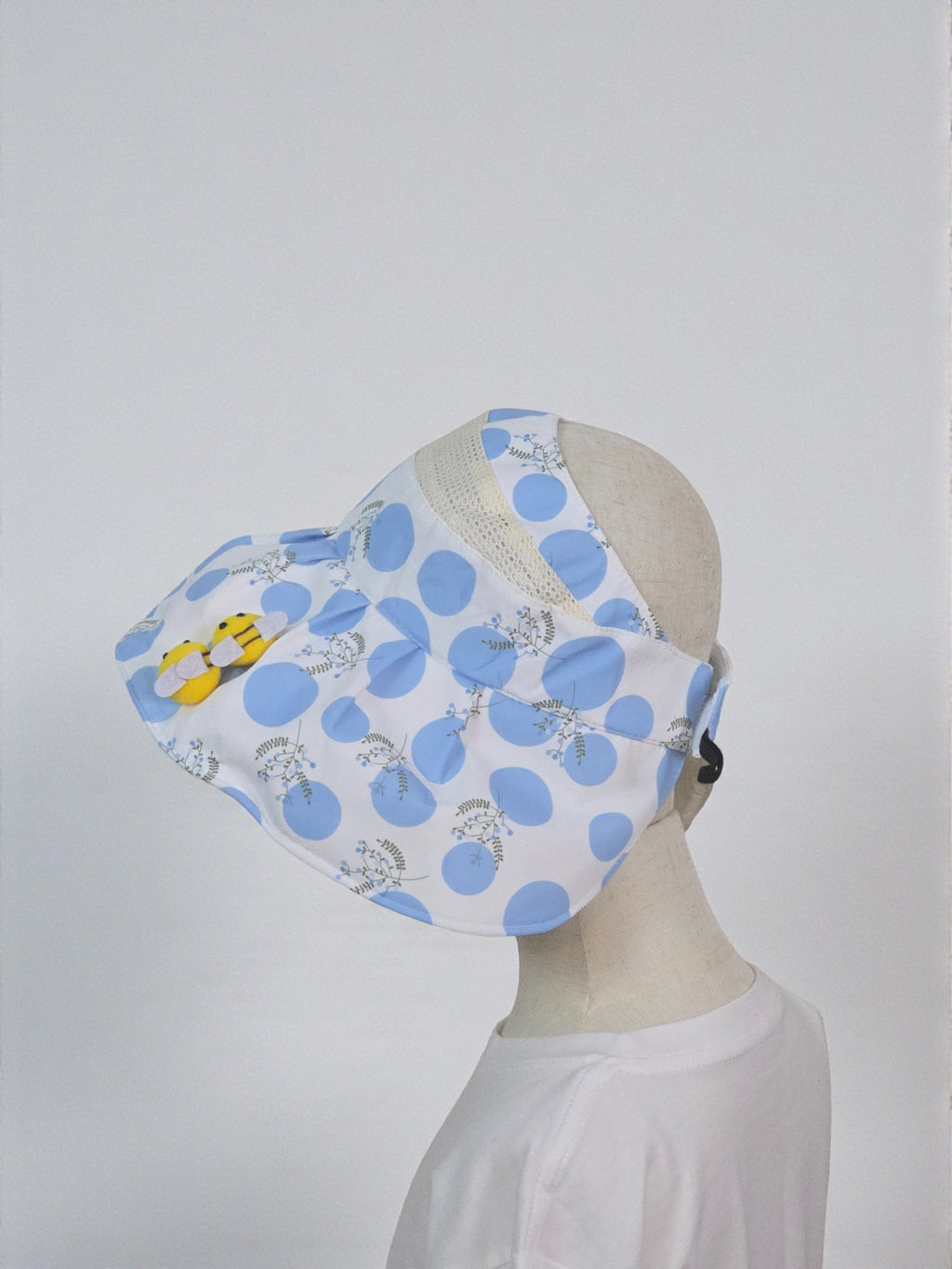 Blue polka dot face mask on a mannequin head against a white background. Blue