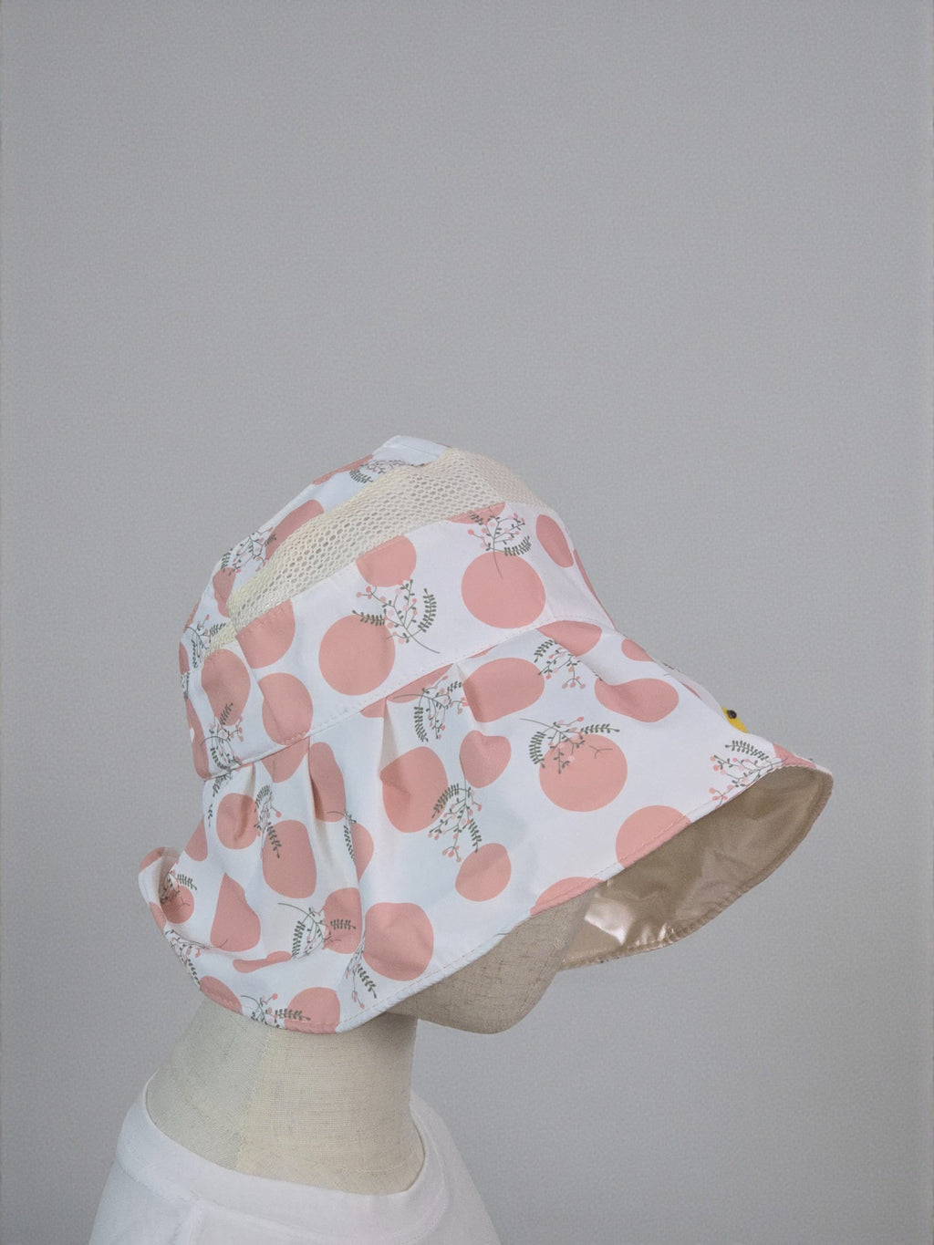 Bucket hat with pink floral pattern on a mannequin head against a gray background. Pink
