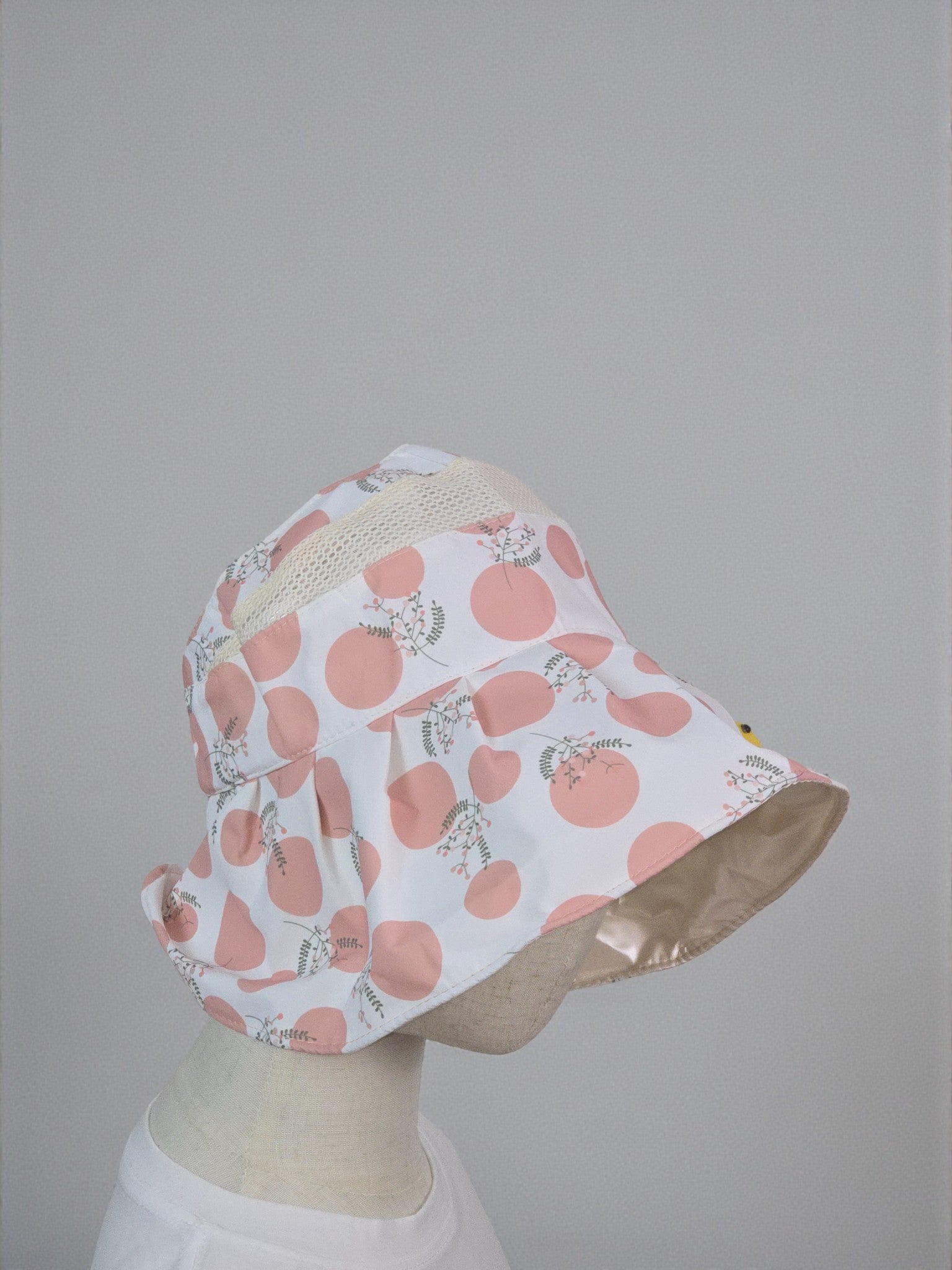 Bucket hat with pink floral pattern on a mannequin head against a gray background. Pink