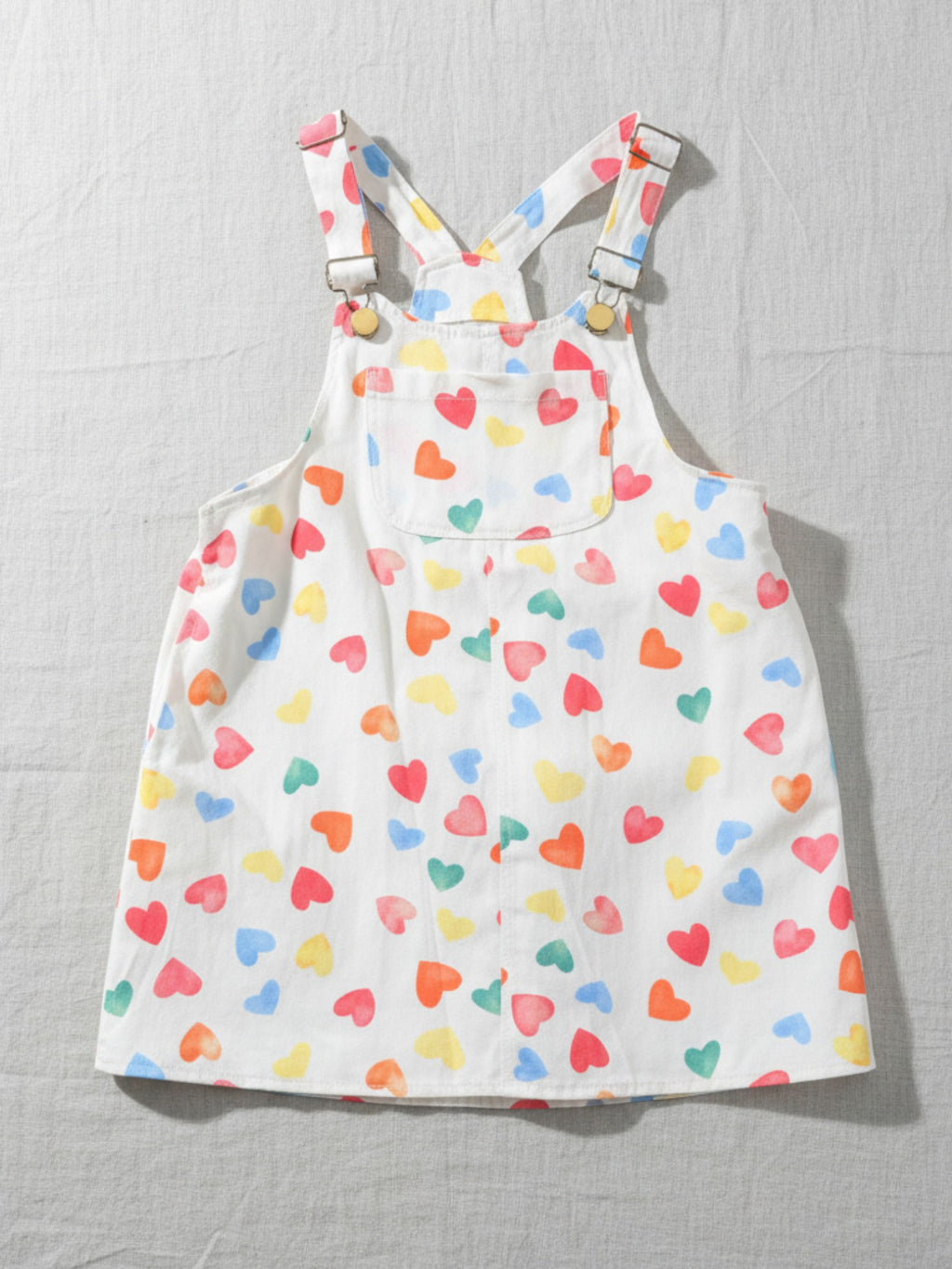 white kids' overalls dress with colorful heart print, versatile and durable cotton fabric for stylish and comfortable play.
