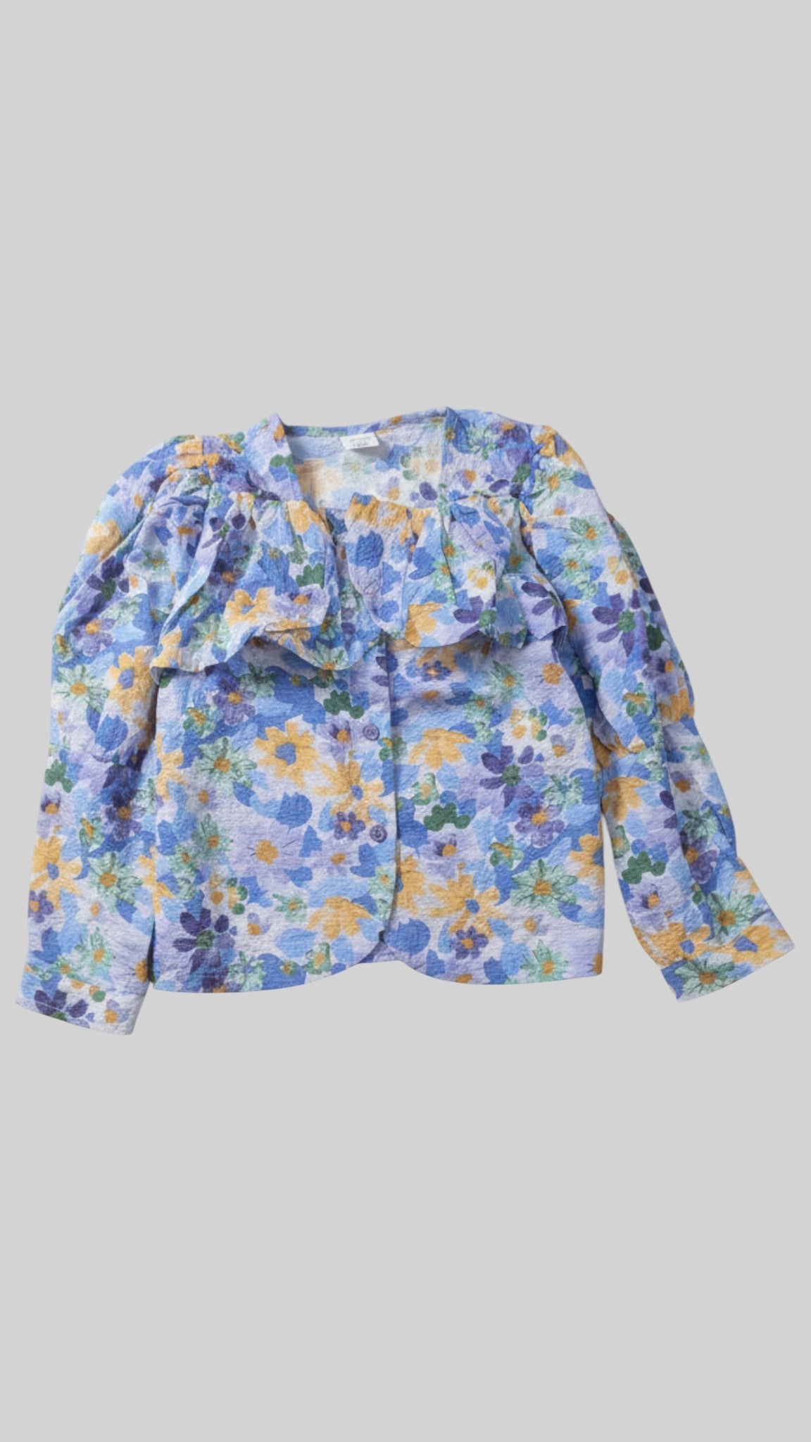 Children's blue floral print blouse featuring a ruffled yoke, long sleeves with gathered shoulders, and a button-up front.