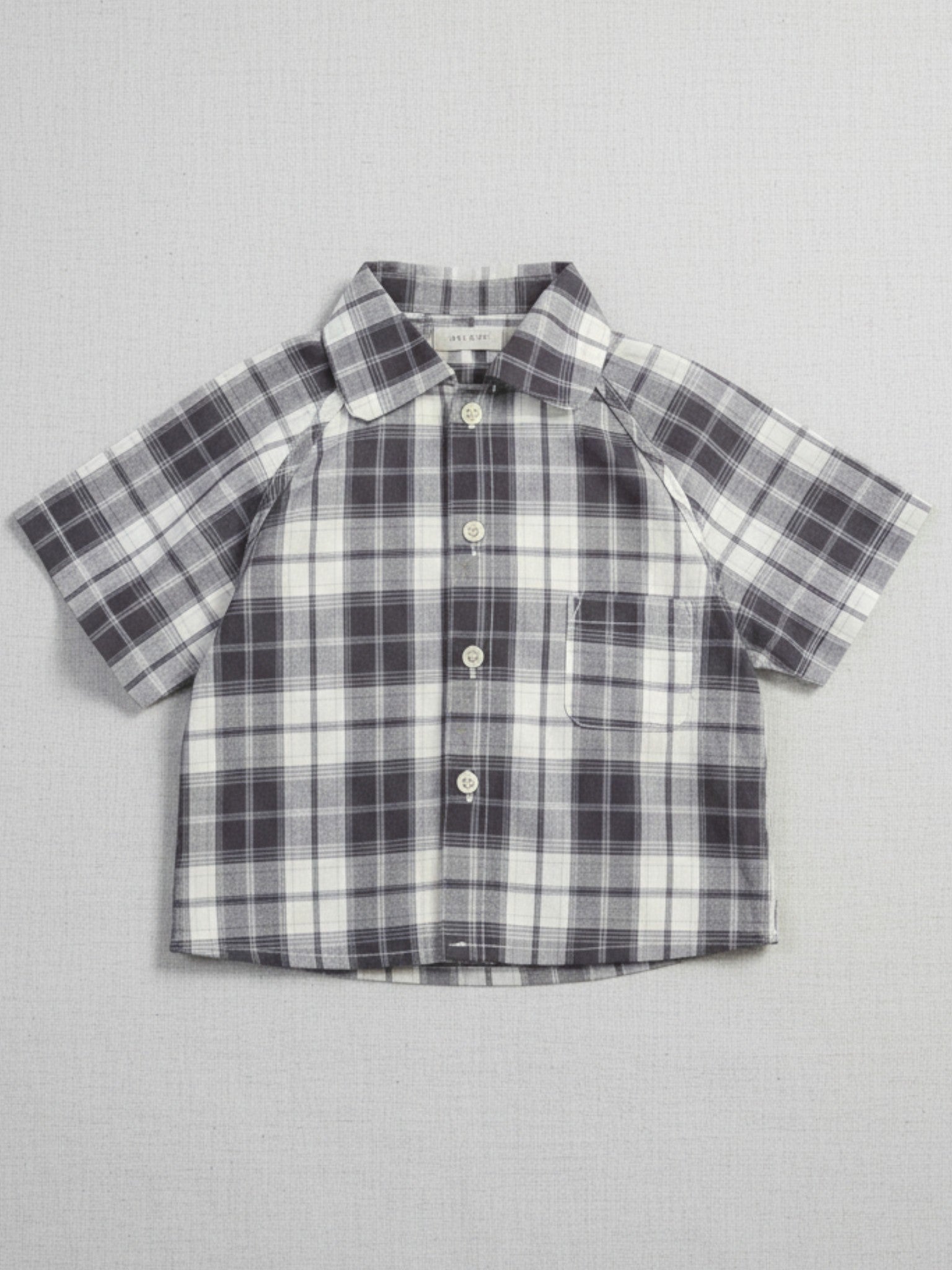 Kids black and cream plaid short sleeve button-down shirt with a chest pocket