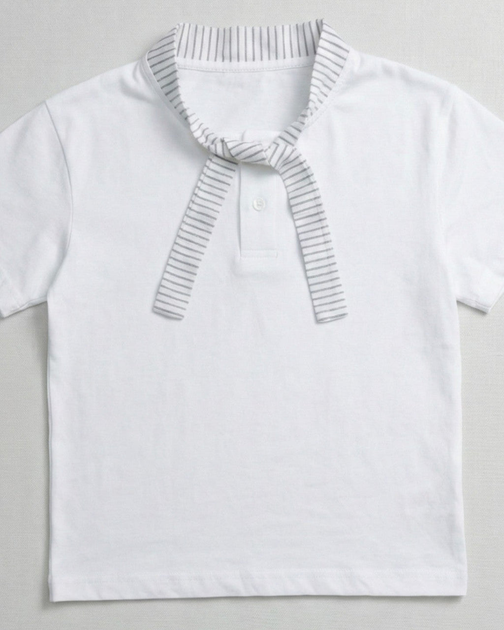 Children's white short-sleeve polo shirt featuring a dark teal contrast collar and placket with a colorful block graphic on the chest.