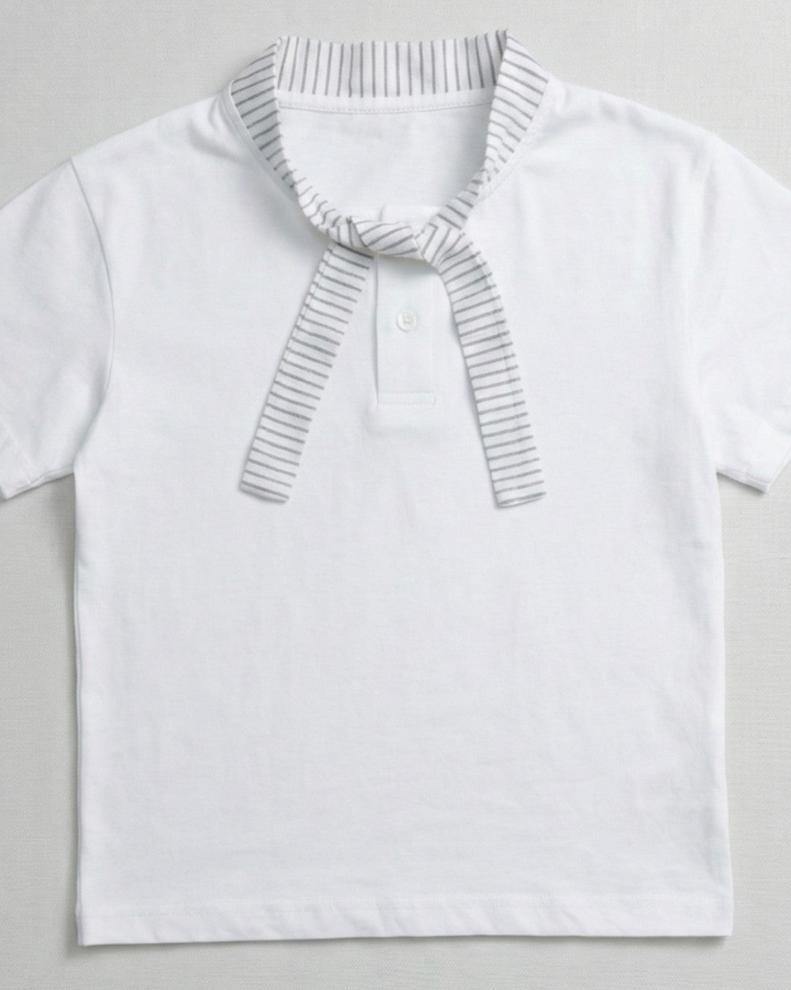 Children's white short-sleeve polo shirt featuring a dark teal contrast collar and placket with a colorful block graphic on the chest.